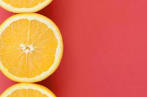 Top view of a several orange fruit slices on bright background in red color. A saturated citrus texture image photo