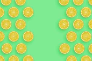 Frame of yellow lemon citrus slices on bright green background photo