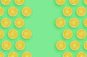 Frame of yellow lemon citrus slices on bright green background photo