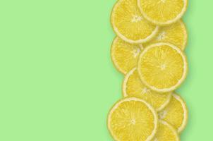 Row of yellow lemon citrus slices on bright lime background photo