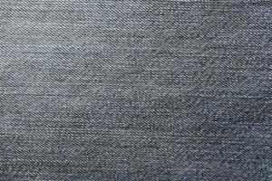 Detailed abstract texture of dark blue denim cloth. Background image of old used denim trousers fabric photo