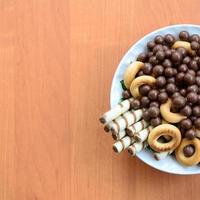 Crispy tubules, chocolate melting balls and bagels lie in a white plate on a wooden table. Mix of various sweets photo