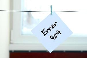 Error 404. Note is written on a white sticker that hangs with a clothespin on a rope on a background of window glass photo