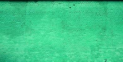 The texture of the brick wall of many rows of bricks painted in green color photo