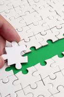 The human hand paves the way to the surface of the jigsaw puzzle, forming a green space. The concept of overcoming the difficulties on the way to success photo