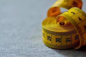 Yellow measuring tape lies on a gray knitted fabric photo