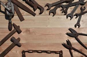 A set of old and rusty tools lies on a wooden table in the workshop photo