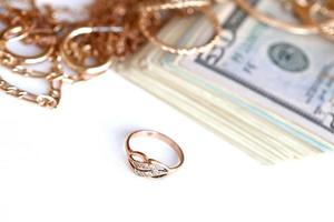 Many expensive golden jewerly rings, earrings and necklaces with big amount of US dollar bills on white background. Pawnshop or jewerly shop photo