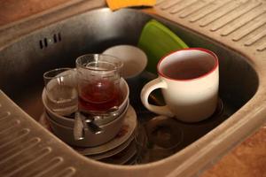 Stack of dirty dishes with food leftovers in the kitchen sink. Unwashed dishes photo