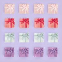 Piles of a small colored gift boxes with ribbons lies on a violet background. Minimalism flat lay top view pattern photo