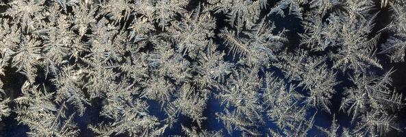 Snowflakes frost rime macro on window glass pane photo