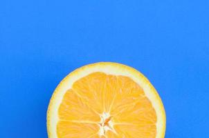 Top view of a one orange fruit slice on bright background in blue color. A saturated citrus texture image photo