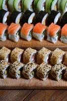 A macro shot of a sushi set of many rolls is located on a wooden cutting board on a table in the kitchen of a sushi bar. A traditional dish of Japanese cuisine photo