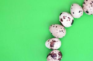 Quail eggs on a light green surface, top view, empty place for t photo