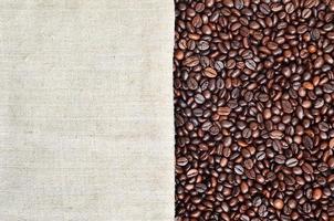 Texture of a gray canvas made of old and coarse burlap with coffee beans on it photo