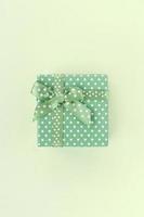 Small green gift box with ribbon lies on a lime background photo