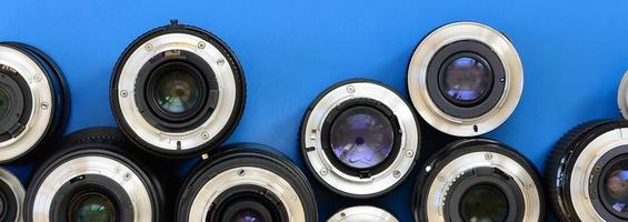 Several photographic lenses lie on a bright blue background. Space for text photo