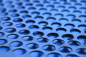 Black metal computer case panel mesh with holes on blue background. Abstract close up image photo