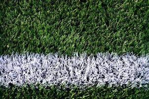 White stripe on a bright green artificial grass soccer field photo