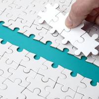 The human hand paves the way to the surface of the jigsaw puzzle, forming a blue space. The concept of overcoming the difficulties on the way to success photo