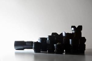 Many different professional lenses for SLR camera lies on a colorless desk photo