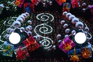 un fragmento de un enorme árbol de navidad con muchos adornos, cajas de regalo y lámparas luminosas. foto de un árbol de navidad decorado de cerca