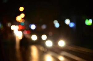 Blurred night scene of traffic on the roadway. Defocused image of cars traveling with luminous headlights. Bokeh Art photo