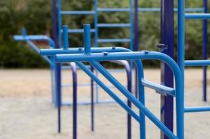 Sports bars in blue on the background of a street sports ground for training in athletics. Outdoor athletic gym equipment. Macro photo with selective focus and extremely blurred background