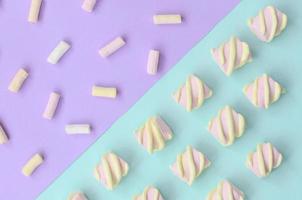 Colorful marshmallow laid out on violet and blue paper background. pastel creative textured pattern. minimal photo