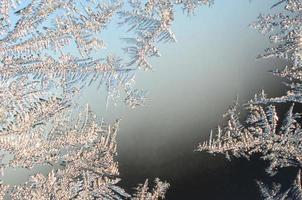 Snowflakes frost rime macro on window glass pane photo