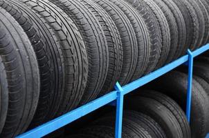Rack with variety of car tires in automobile store. Many black tires. Tire stack background. Selective focus photo