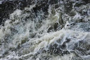 Waves of water of the river and the sea meet each other during high tide and low tide. Deep blue stormy sea water surface with white foam and waves pattern, background photo