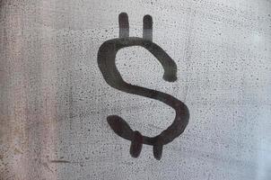 The dollar symbol on the misted sweaty glass. Abstract background image. US money concept photo