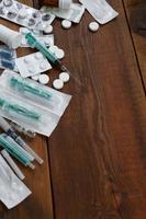 Narcotic stuff with many pills and syringes lies on wooden table and ready to use photo