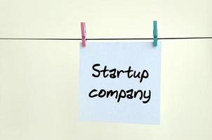 Startup company. Note is written on a white sticker that hangs with a clothespin on a rope on a background of beige wall photo