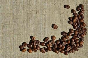 Texture of a gray canvas made of old and coarse burlap with coffee beans on it photo