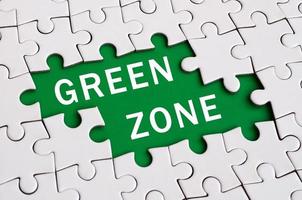 White jigsaw puzzle in assembled state with missing elements forming a green space with white inscription. Green zone photo