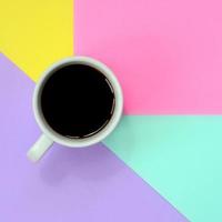 Small white coffee cup on texture background of fashion pastel blue, yellow, violet and pink colors paper in minimal concept photo