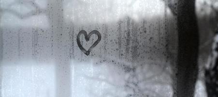 The heart is painted on the misted glass in the winter photo