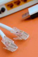 Internet router, portable USB wi-fi adapter and internet cable plugs lie on a bright orange background. Items required for internet connection photo