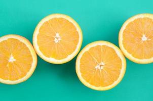 Top view of a several orange fruit slices on bright background in turquoise green color. A saturated citrus texture image photo