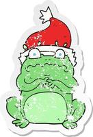 retro distressed sticker of a cartoon frog in christmas hat vector