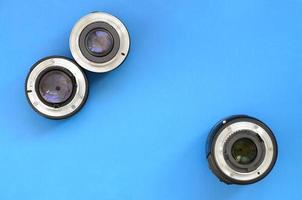 Several photographic lenses lie on a bright blue background. Space for text photo