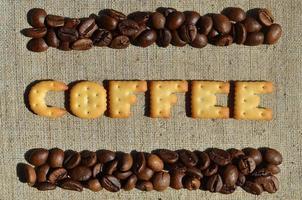 café. la palabra de las letras comestibles se encuentra en el lienzo gris con granos de café foto