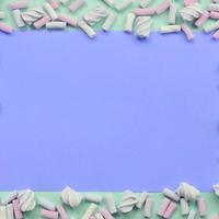 Colorful marshmallow laid out on green and lilac paper background photo