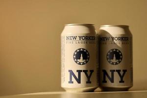 TERNOPIL, UKRAINE - JULY 18, 2022 Two cans of New Yorker fine lager beer with original logo and design on brown retro background photo