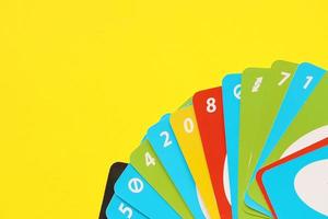 TERNOPIL, UKRAINE - MAY 15, 2022 Many colorful UNO game cards on yellow background. UNO is an American shedding-type card game that is played with a specially printed deck photo