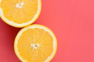 Top view of a several orange fruit slices on bright background in red color. A saturated citrus texture image photo