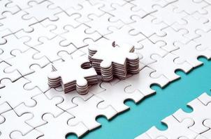 The blue path is laid on the platform of a white folded jigsaw puzzle. The missing elements of the puzzle are stacked nearby. Texture image with space for text photo