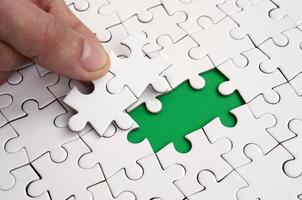 The human hand fills the last missing elements of the surface from the jigsaw puzzle. The concept of the completion of the initiated cases photo